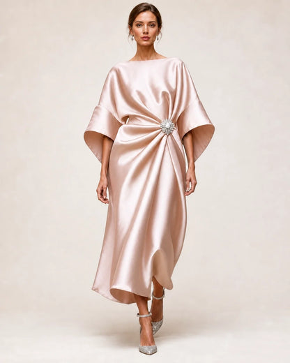 Women's beige blush satin midi dress with draped waist, crystal flower brooch and wide batwing sleeves.