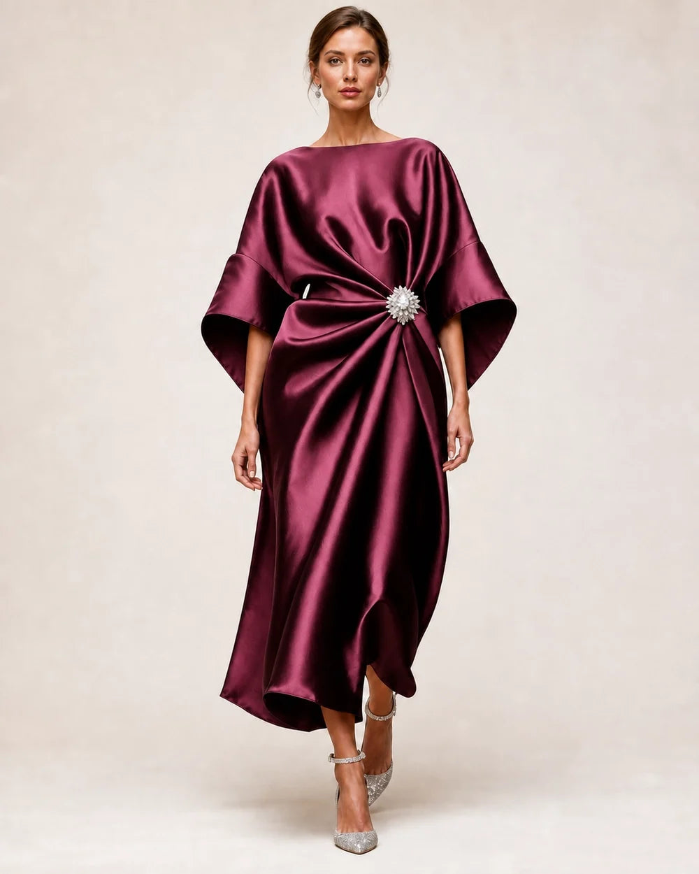 Women's deep red satin midi dress with draped waist, crystal flower brooch and wide batwing sleeves.