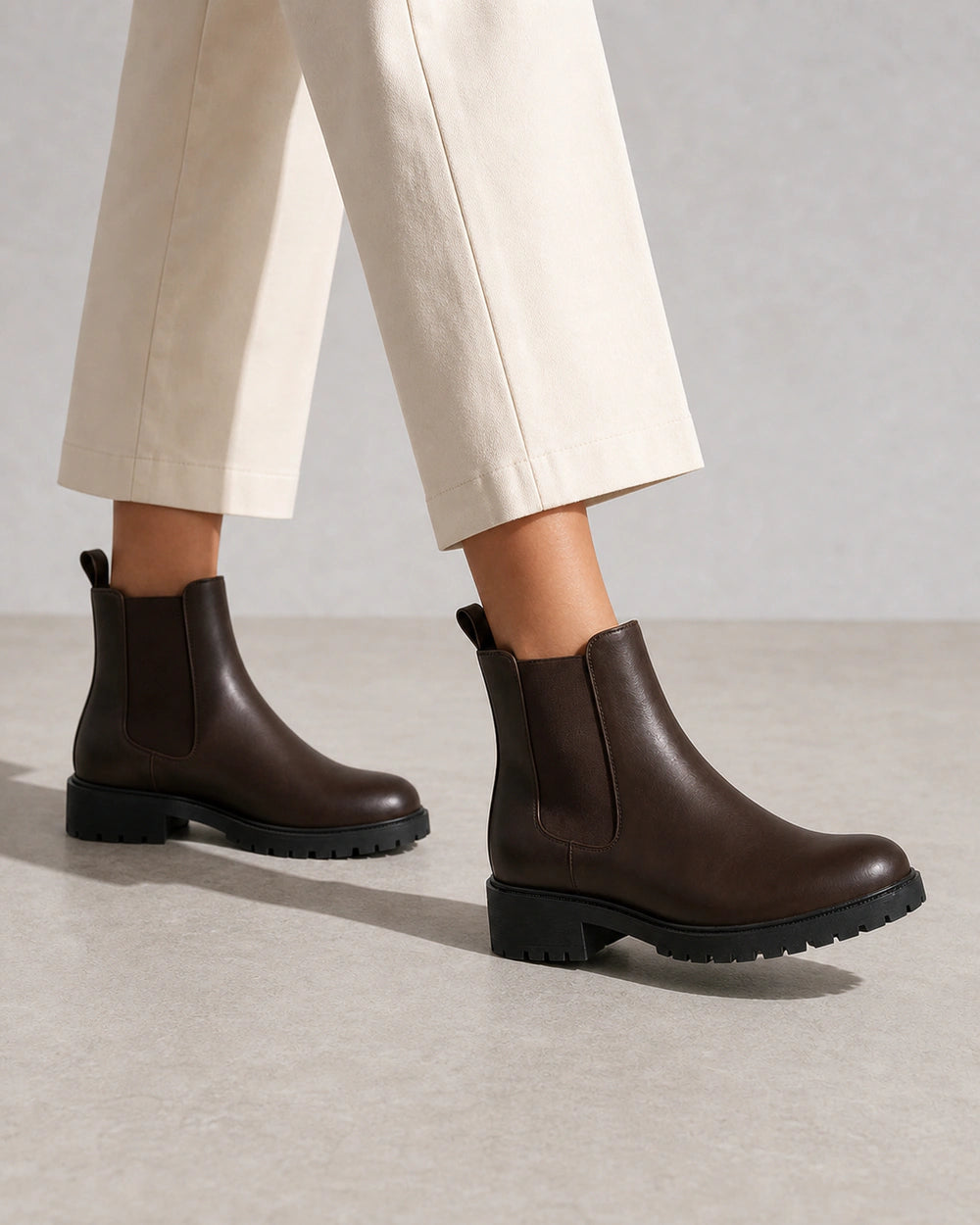 Women's chocolate brown lug-sole Chelsea boots, walking view.